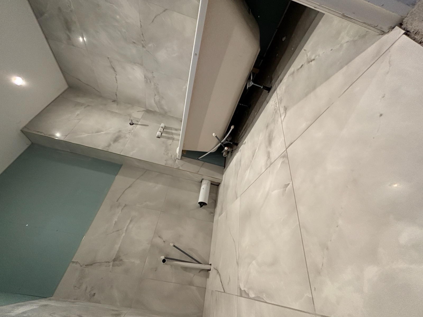 Polished marble-effect floor and wall tiling around a freestanding bath